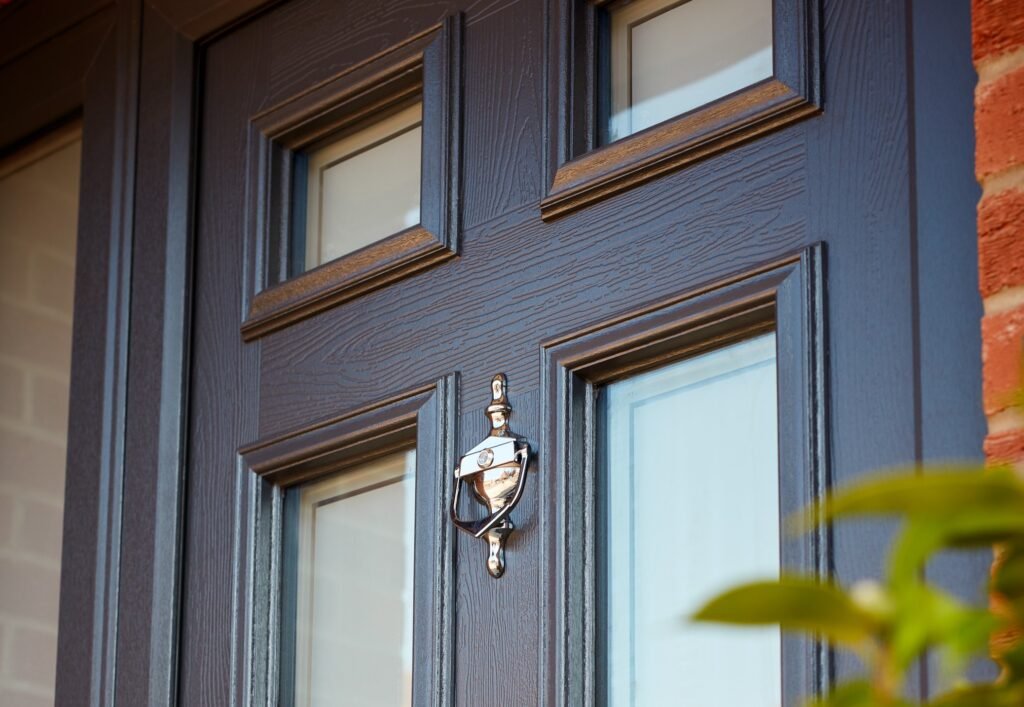 Dark woodgrain entrance door with square glazing and a chrome knocker